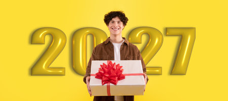 Person Holds Gift Box in Front of Large Numbers Celebrating the Year 2027の写真素材