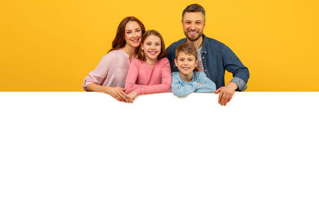Happy family peeking over a white boardの写真素材
