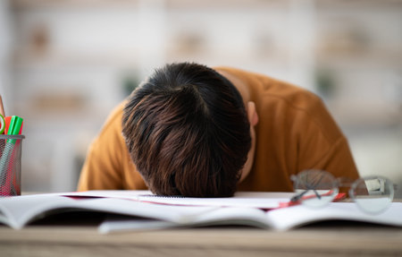 Sleeping schooler laying on desk full of exercise booksの写真素材