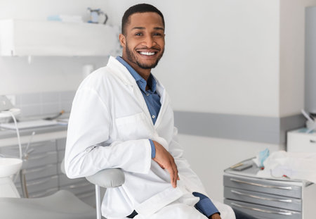 Cheerful black man stomatologist resting at workplaceの写真素材