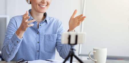 Woman Talks During Online Meeting While Sitting at Desk With Coffee Cup