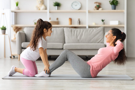 Cute mother and daughter working on abs muscles togetherの写真素材