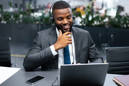 Man in Suit Working on Laptop With Headset in Modern Office During Daytime