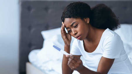 Woman Looking Worried While Holding Pregnancy Test in Bedroom During Morning Hoursの写真素材