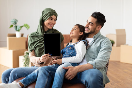 Happy muslim family doing repair woman showing tabletの写真素材