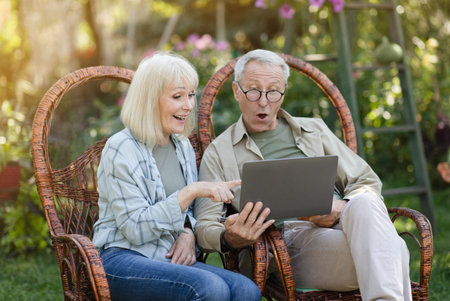 Wow. Senior married couple looking at laptop, surprised by good unbelievable news, surfing internet,...