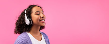 Listening to Music With Headphones While Smiling Against a Pink Background at Home