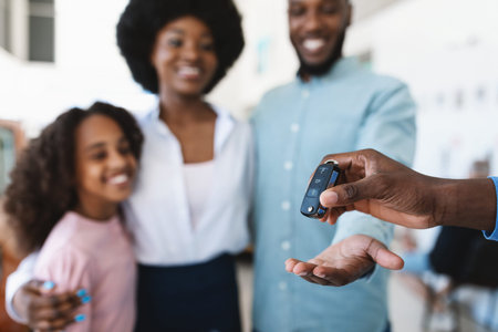 Manager giving new car key to young black family at auto dealership store, selective focusの写真素材