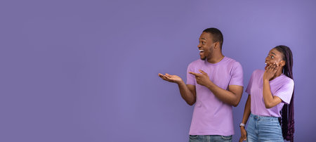 Excited couple pointing aside at free copy space, panorama