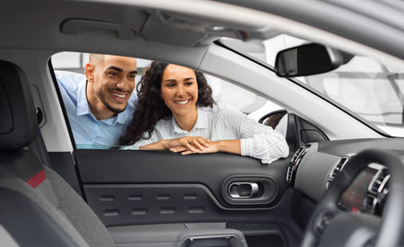 Cheerful young couple buying new car, checking salon
