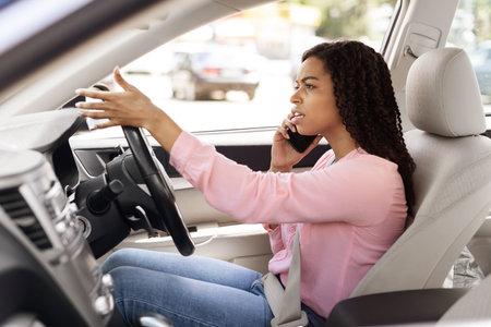 Angry black woman talking on cell phone while driving car
