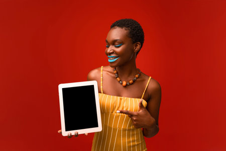Beautiful african american woman fashionista pointing at digital tablet, mockupの写真素材