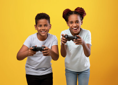 Joyful black brother and sister holding joysticksの写真素材