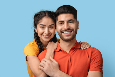 Cheerful Young Couple Poses Together Against a Bright Blue Background With Warm Smiles and Playful Expressionsの写真素材