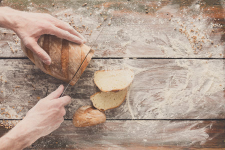 Bakery concept background. Hands cutting bread loaf slicesの写真素材