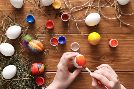 Efforts in Creating Colorful Easter Eggs With Paint and Brushes on a Wooden Table