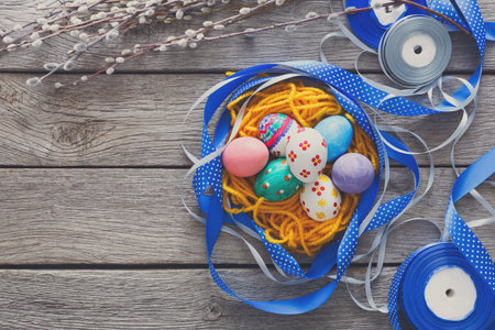 Colorful Easter Eggs Surrounded by Ribbons and Spring Decorations on a Wooden Background