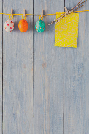 Colorful Easter Eggs and a Yellow Note on a Wooden Background for Spring Decoration