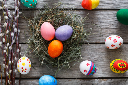 Colorful Easter Eggs Arranged Around a Nest of Hay on a Wooden Table