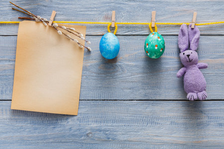 Colorful Easter Decorations With Eggs and a Bunny on a Wooden Background Featuring a Blank Noteの写真素材