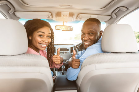 Happy black couple sitting in auto gesturing thumbs upの写真素材