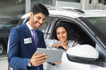 Pretty lady sitting inside car, having conversation with sales assistantの写真素材