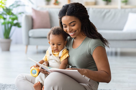 Caring African American Mommy Reading Book For Her Toddler Son At Home