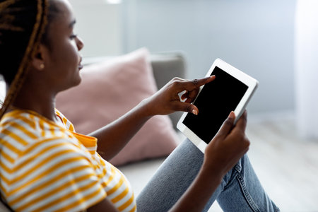 Side view of black woman using pad with empty screen