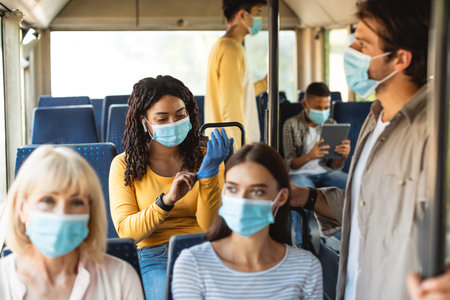 African American woman wearing medical mask and gloves taking bus