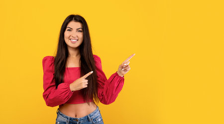Happy armenian woman pointing fingers at free space over yellow background, panoramaの写真素材