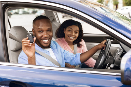 Happy black couple sitting in car showing keysの写真素材