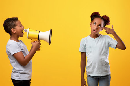 Black boy with loudspeaker yelling at his sisterの写真素材