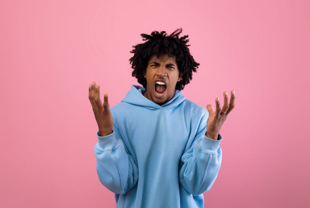 Angry teenager shouting on pink studio backgroundの写真素材