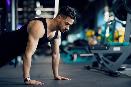 Muscular Arab Guy Doing Floor Push Up Exercise While Training In Gym
