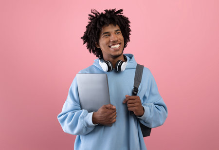 Portrait of smiling teen guy posing with tablet computer, headphones and backpack, ready to start schoolの写真素材