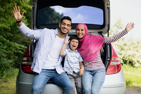 Portrait Of Happy Arab Family With Little Son Sitting In Car Trunkの写真素材