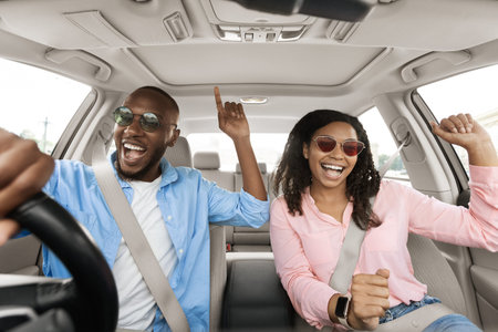 Happy black couple enjoying music driving luxury car