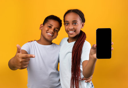Adorable black teens brother and sister showing smartphone, mockup