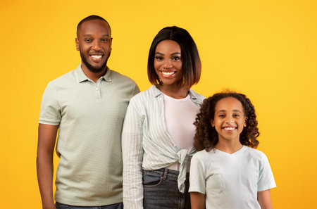 People, family portait concept. Happy african american man, woman and girl posing for photo and smiling to cameraの写真素材