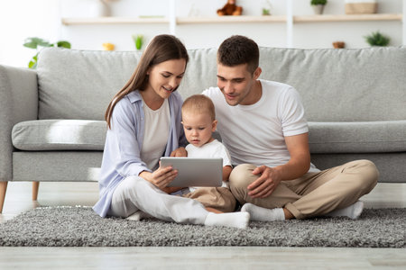 Family Leisure. Millennial Parents With Toddler Son Using Digital Tablet At Home