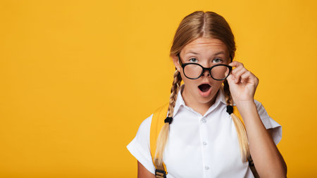 Shocked teenager schoolgirl with pigtails, open mouth, takes off glassesの写真素材