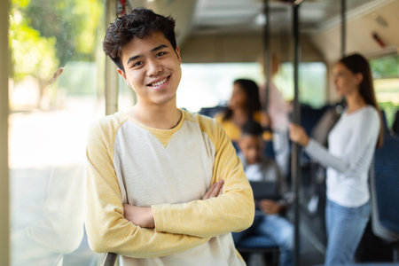 Smiling asian guy taking bus, looking at cameraの写真素材