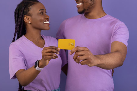 Happy black couple hugging and holding credit card