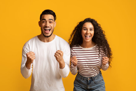 Hooray. Euphoric Middle Eastern Couple Raising Fists And Exclaiming With Excitement