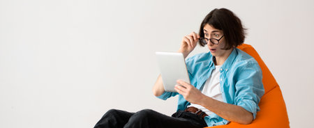 A Person is Sitting in an Orange Chair While Holding a Tablet