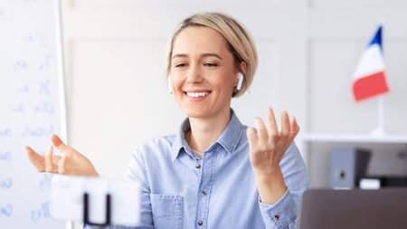 Woman Engages in Online Conversation While Using Earbuds in an Office Setting in the Afternoon