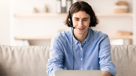 Young Man Working on Laptop With Headset in Modern Living Space During Daytime Hours