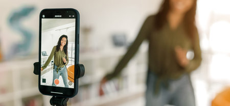 Woman Shooting a Dance Video in a Bright Room With a Smartphone on a Tripod for Recording