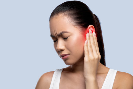 Woman Experiences Ear Pain While Holding Her Head in Discomfort at Home