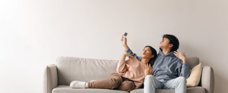 Couple Sharing a Moment While Taking a Selfie on a Sofa in a Cozy Living Roomの写真素材